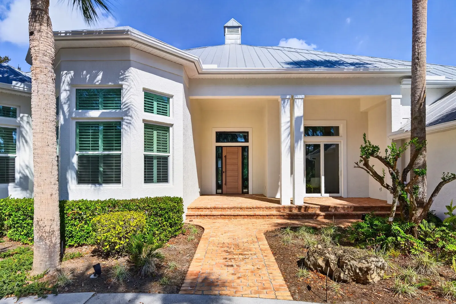 Gallery 5 Stucco coastal home exterior with metal roof and palm trees in Venice FL